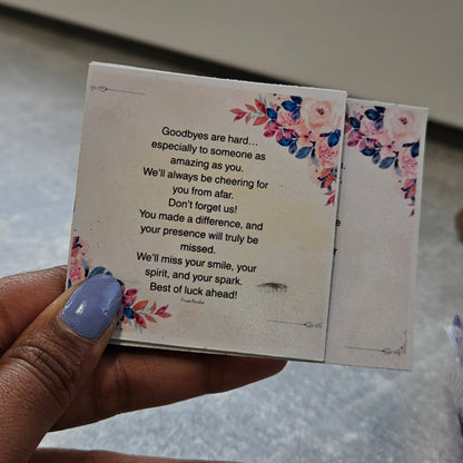 Hand holding a floral card with text on a textured surface